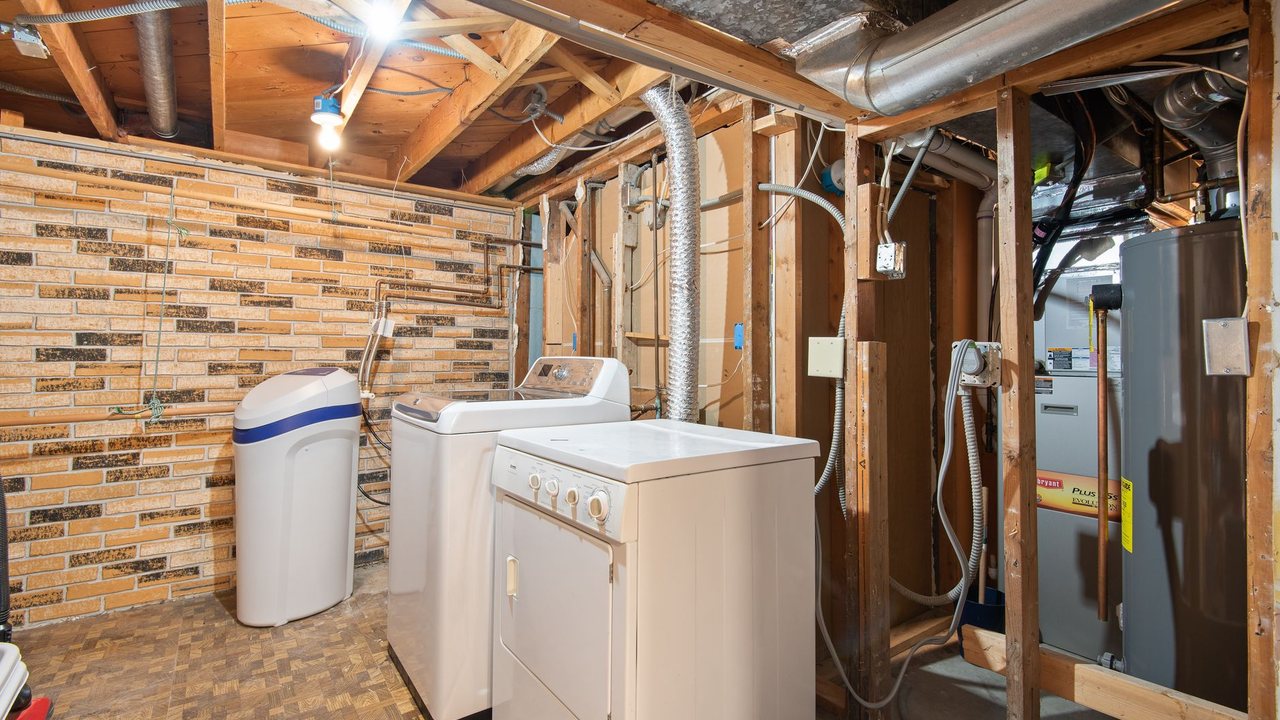 Utility room with laundry appliances and exposed pipework