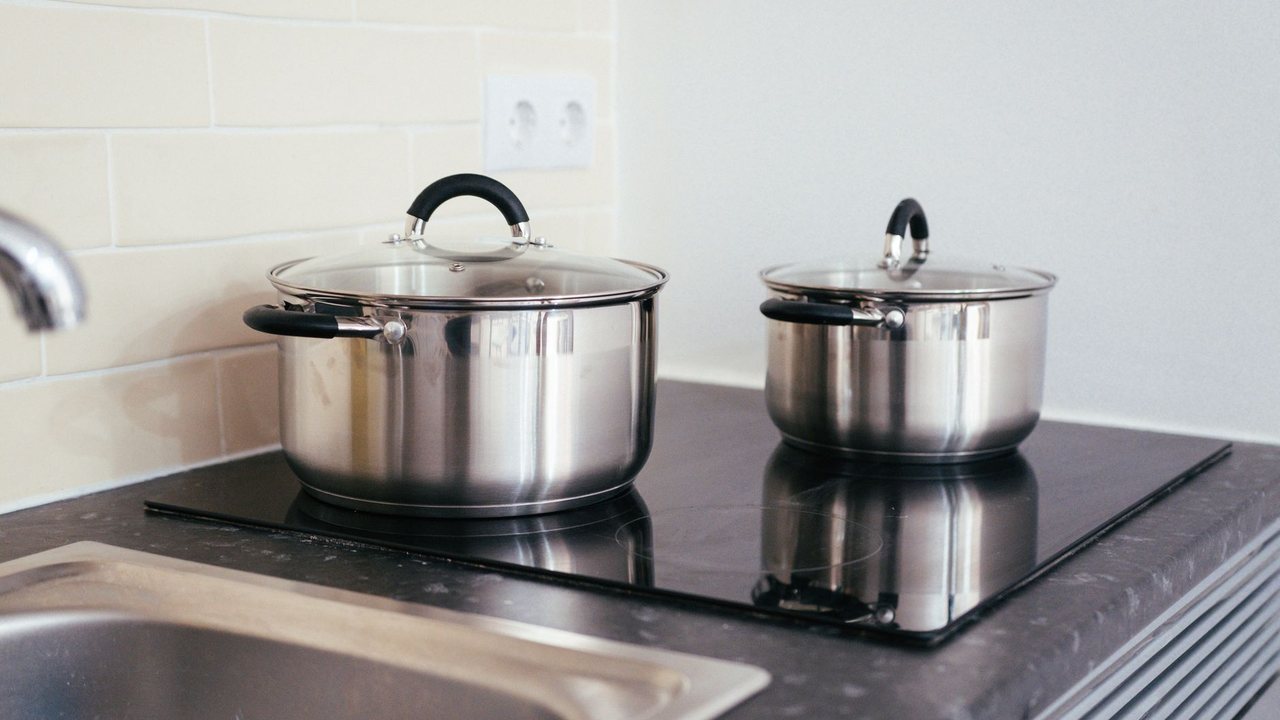Dos ollas de acero sobre una placa de cocina negra