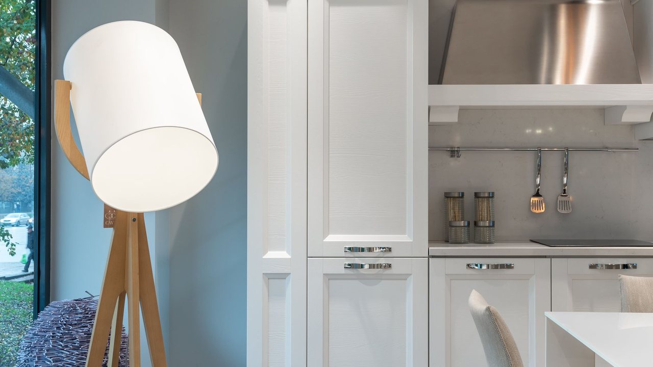 White kitchen with a metal cooker hood and a floor lamp beside the window