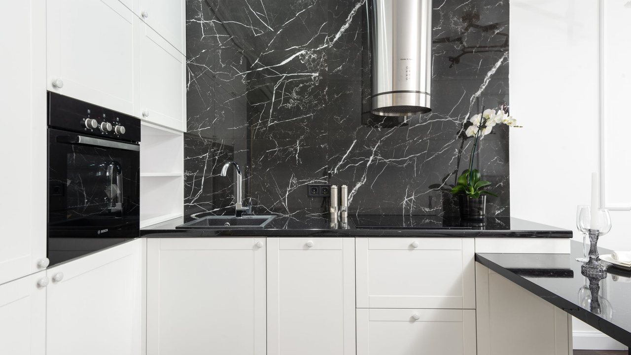 Cylindrical cooker hood above a hob and dark veined splashback