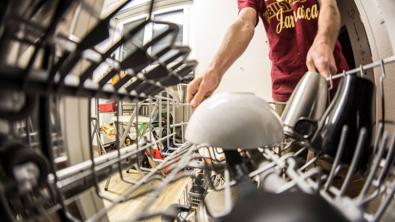 Person placing a plate in a dishwasher rack