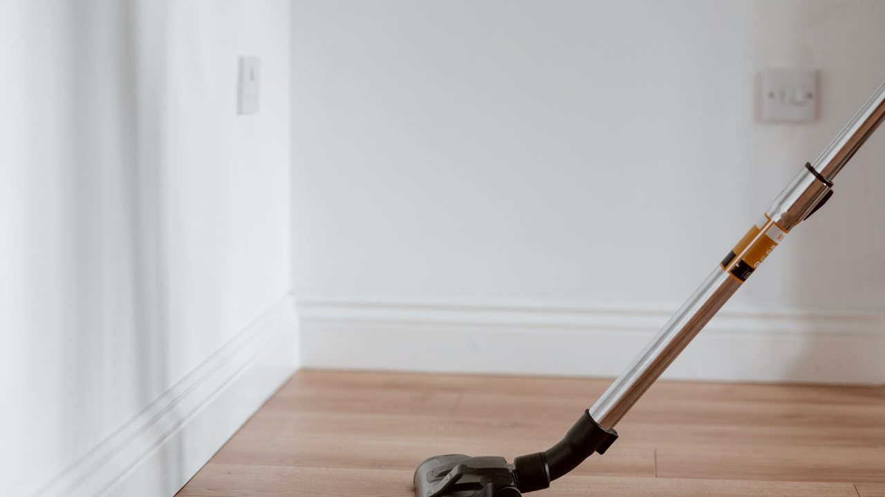 Cabezal de aspirador sobre un suelo de madera en una habitación vacía