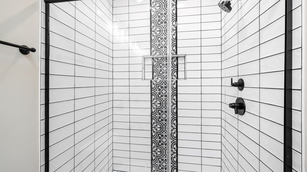 Black-framed shower screen in front of white wall tiles