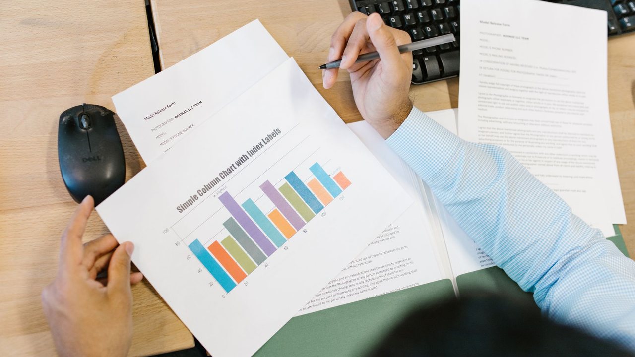 Persona revisando un gráfico de barras impreso en una mesa de trabajo