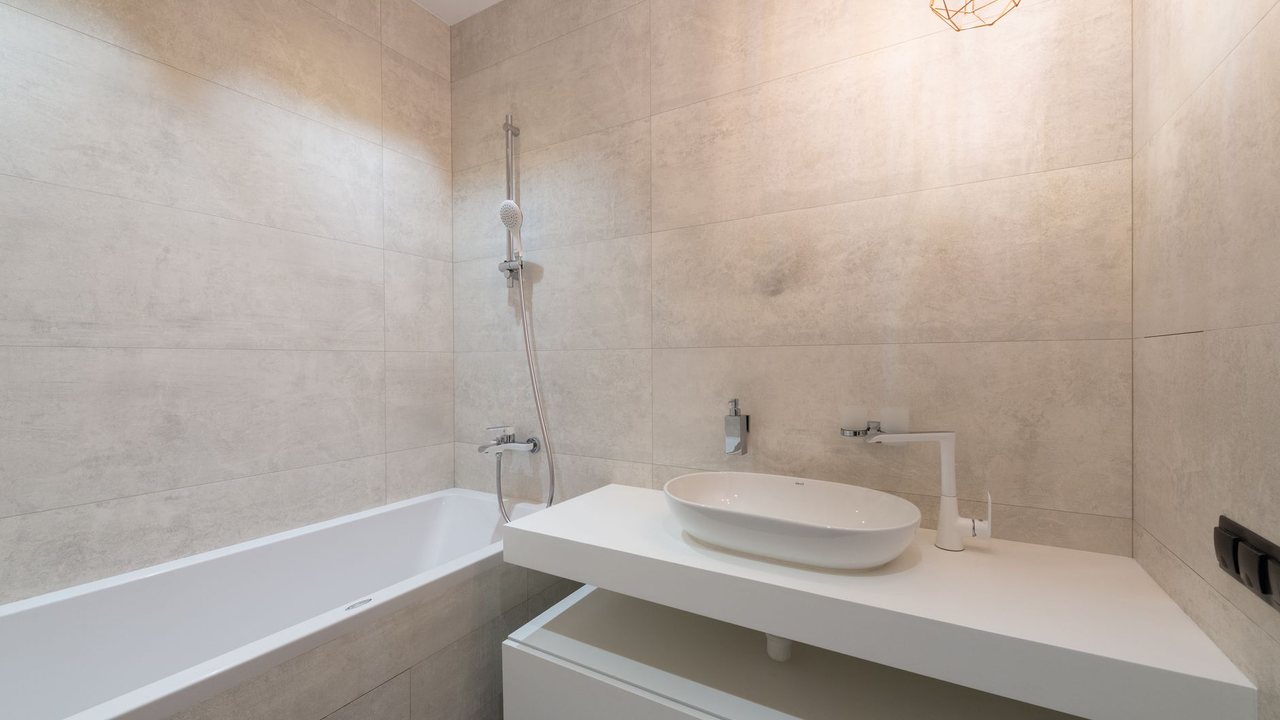 Baño claro con bañera y lavabo sobre mueble blanco