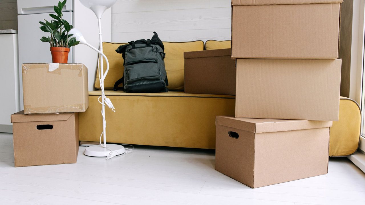Cajas de cartón y una mochila junto a un sofá