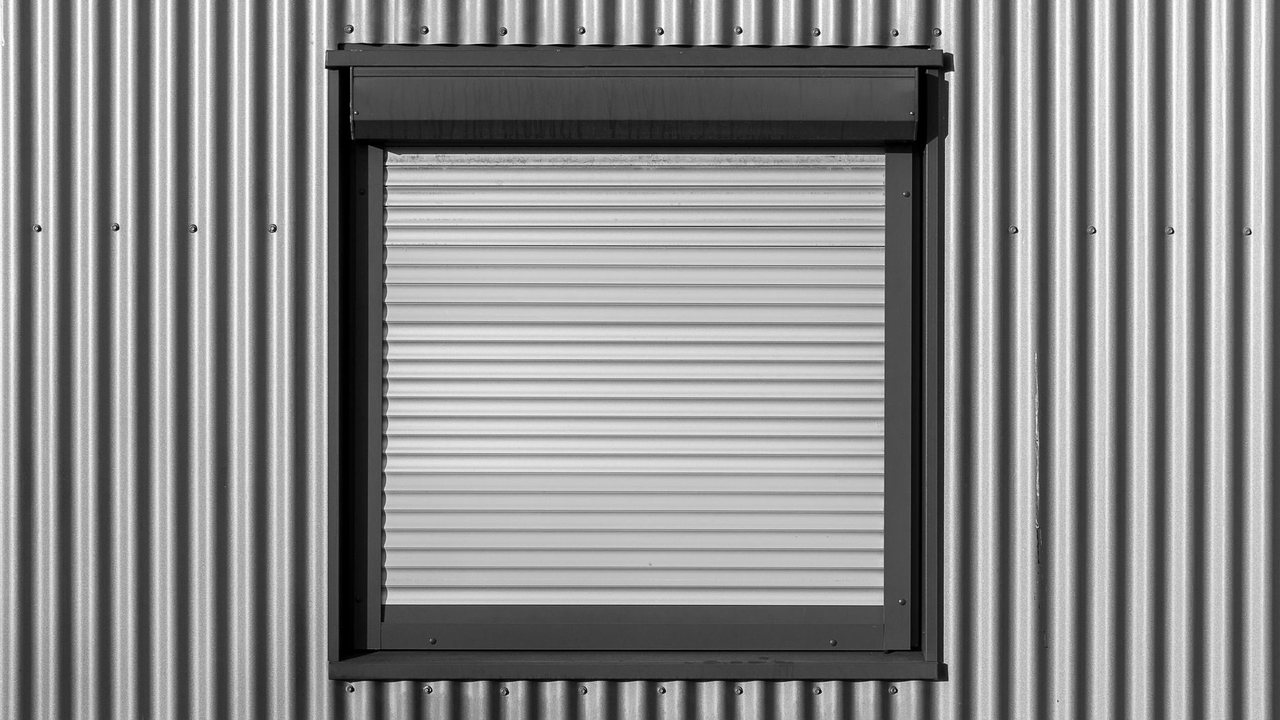 Ventana con persiana enrollable en una fachada metálica