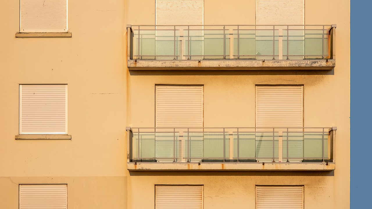 Fachada residencial con balcones y persianas cerradas