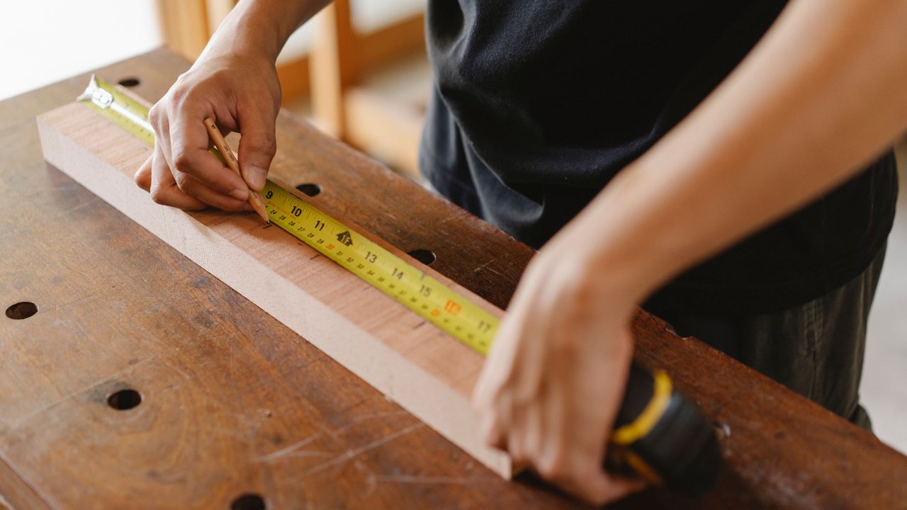 Carpenter measuring a board with a tape measure