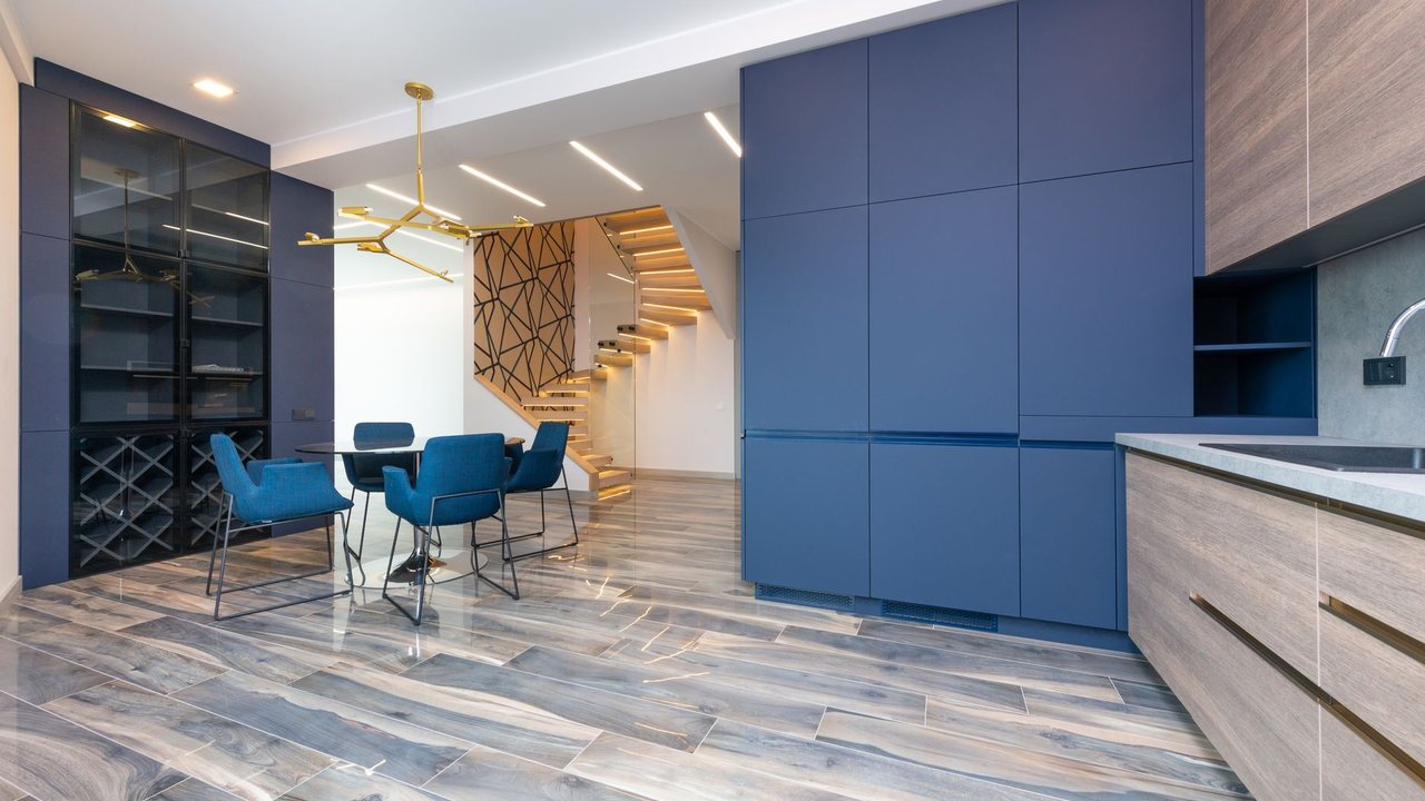 Cocina azul junto a escalera con pavimento de aspecto madera