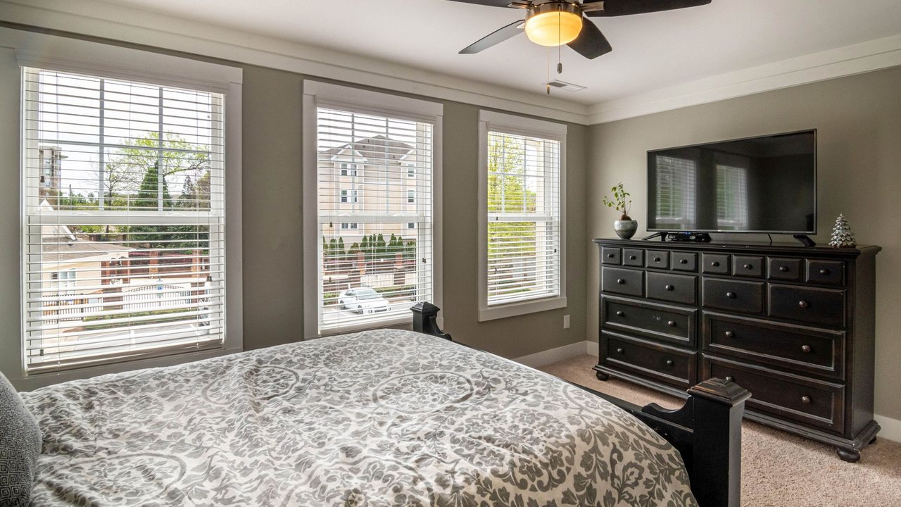 Dormitorio con ventilador de techo, ventanas y mueble de televisión